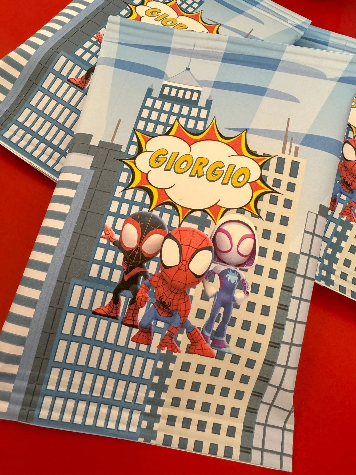 Confezione di merendine con personaggi dei cartoni animati Spider-Man e Gwen Stacy, in stile cartone, con un'illustrazione di un grattacielo di città sullo sfondo.