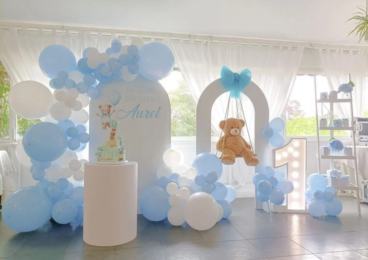 Decorazioni per il primo compleanno di Aurel, con palloncini blu e bianchi, una torta e un orsetto di peluche sospeso